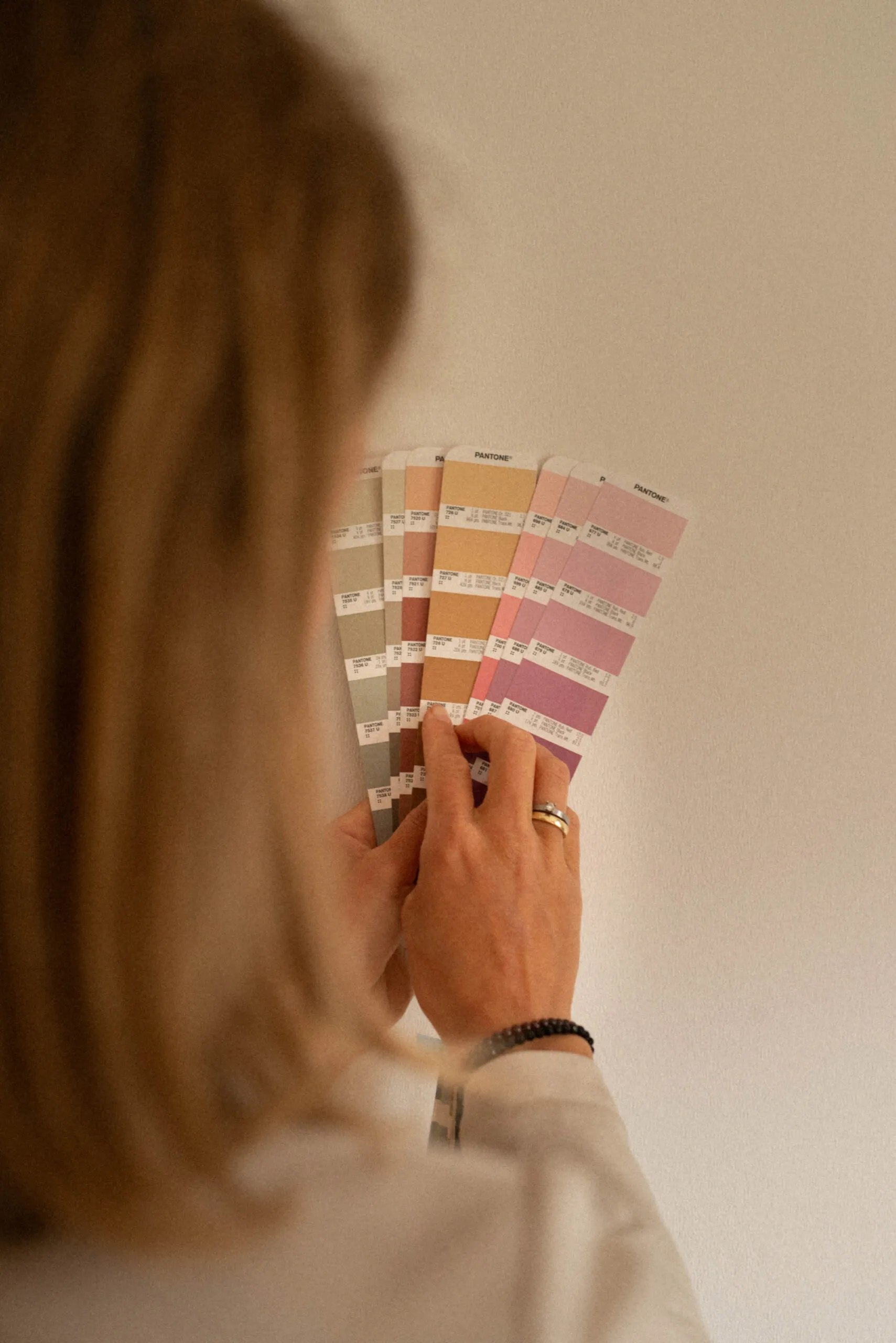 Aufgefächerter Pantone-Farbfächer über der Schulter einer Frau
