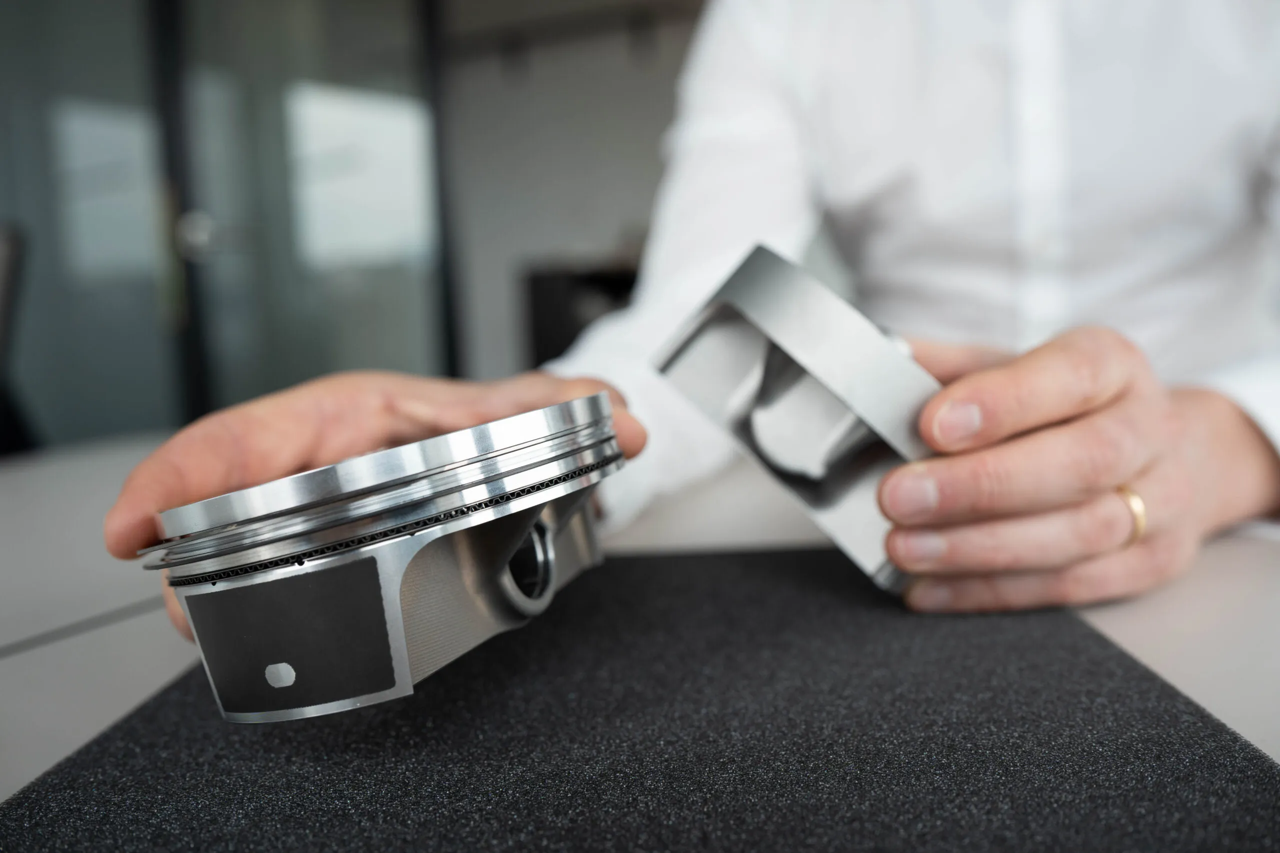 Hände halten zwei glänzende Aluminium-Kolben, Produktdetail