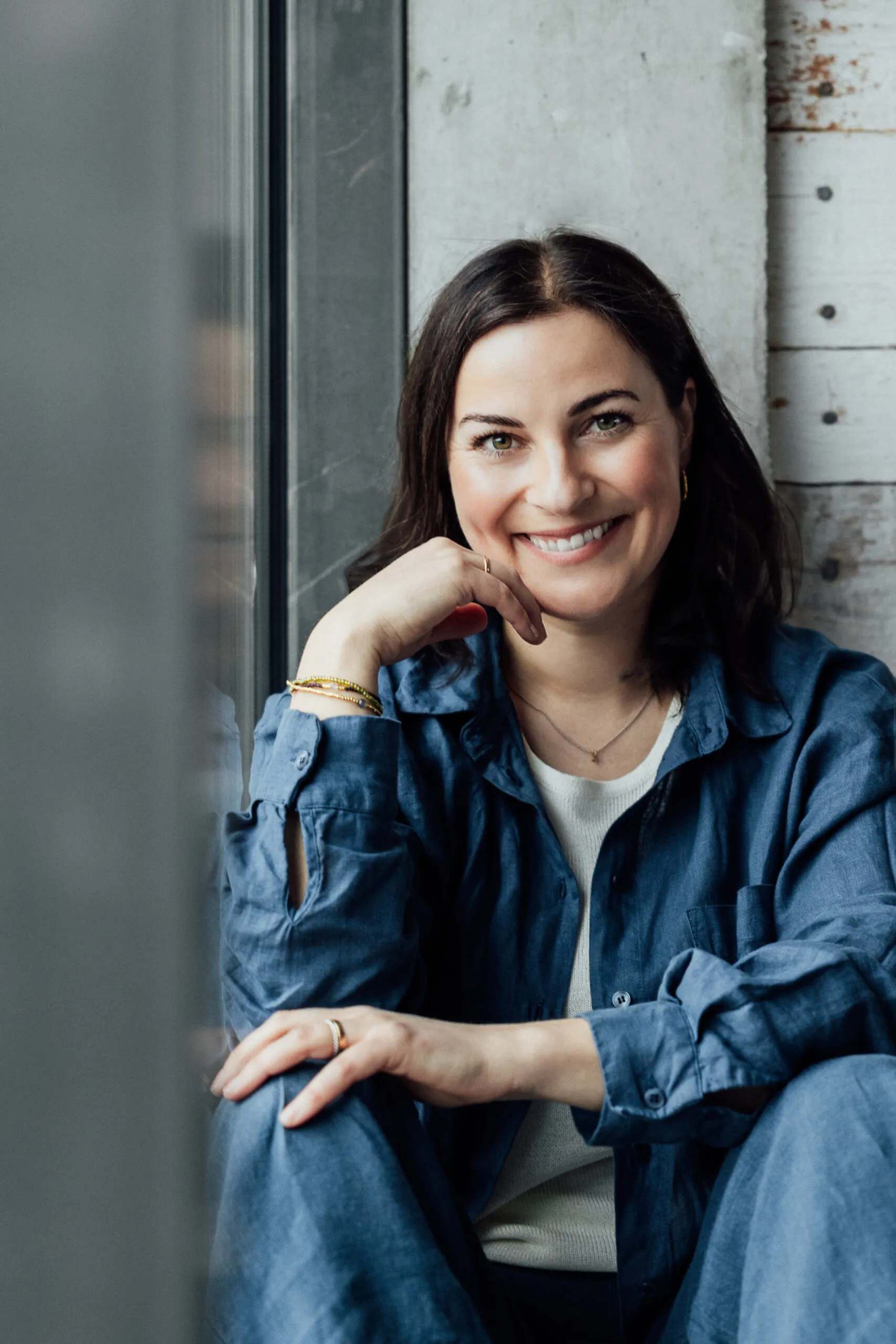 Julia Bechter, Personal-Brand-Fotografin, sitzt lächelnd am Fenster ihres Studios
