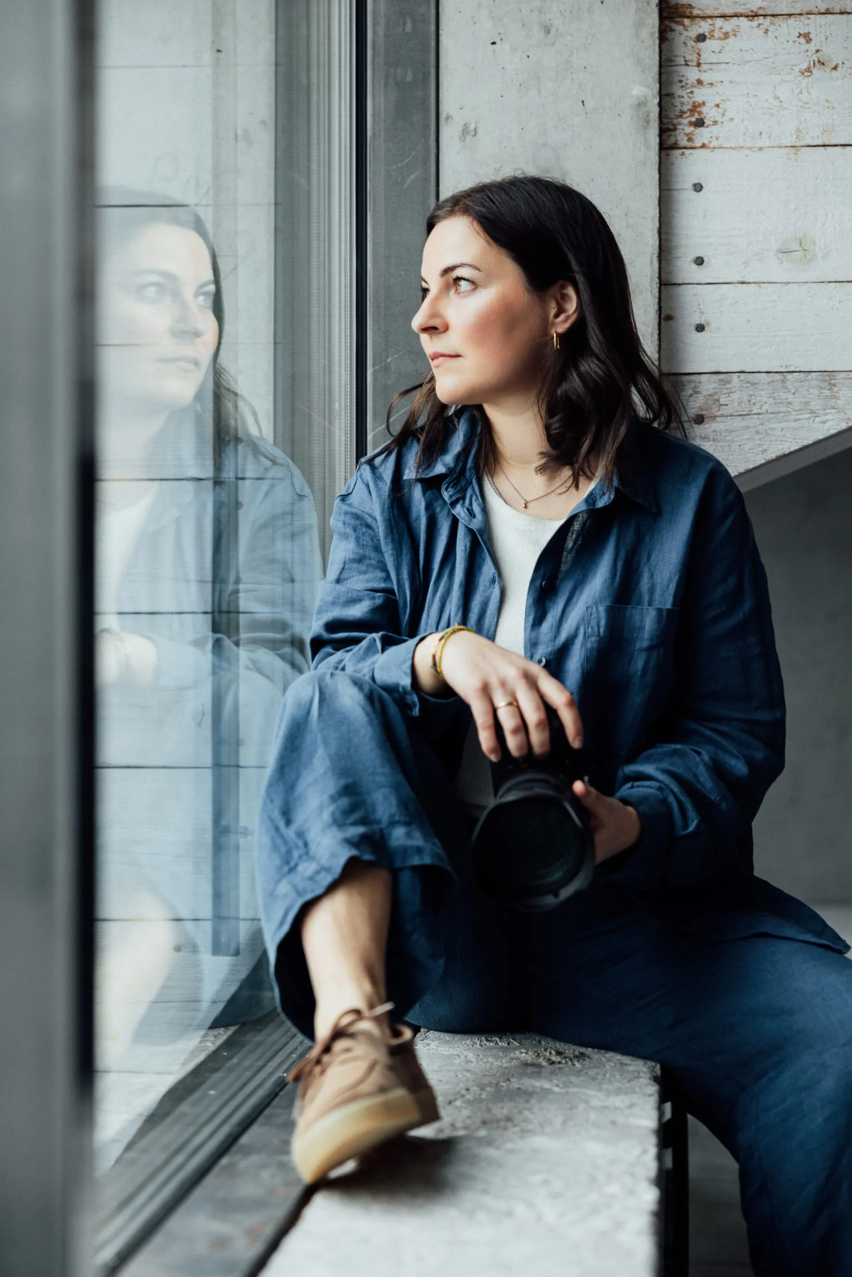 Julia Bechter sitzt mit Kamera in der Hand am Studiofenster